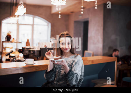Happy smiling young woman using phone in a cafe. Beautiful girl in trendy spring colors Stock Photo