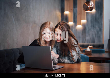 One-on-one meeting.Two young business women sitting at table in cafe.Girl shows colleague information on laptop screen.Meeting friends, dinner together.Teamwork, business meeting. Freelancers working Stock Photo