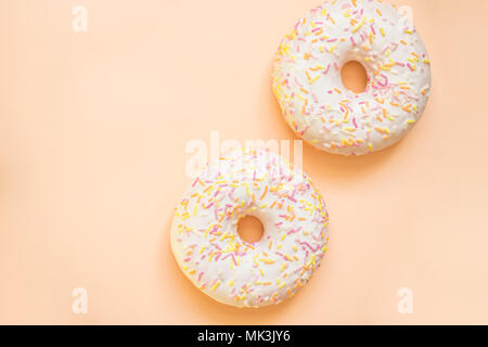 Donut with white icing colored topping, isolated on yellow background.Tasty classic two glazed donuts isolated.Delicious colorful donuts Stock Photo