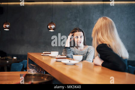 Two friends enjoying coffee together in a coffee shop as they sit at a table chatting Stock Photo