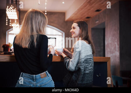 Two friends enjoying coffee together in a coffee shop as they sit at a table chatting