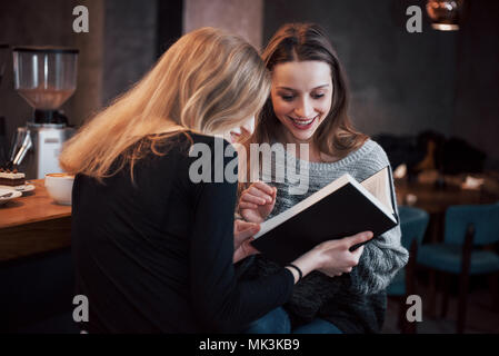 Two young women sitting in the cafe drinking coffee and enjoying in good books. Students on coffee break. Education, lifestyle concept Stock Photo