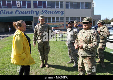 California National Guard representatives meet with a private security sentry Nov. 1 at the Sonoma County Fairgrounds in Santa Rosa, California, one of a few remaining evacuation sites used for homeless victims after the Northern California wildfires. Shown: Maj. Donald L. Lipscomb, operations officer, 579th Engineer Battalion; Senior Master Sgt. Johnny Gatlin, operations superintendent, 146th Security Forces Squadron; and 1st. Sgt. Antonio M. Delgadillo, first sergeant for the 149th CBRN Company. (Army National Guard photo by Staff Sgt Eddie Siguenza) Stock Photo
