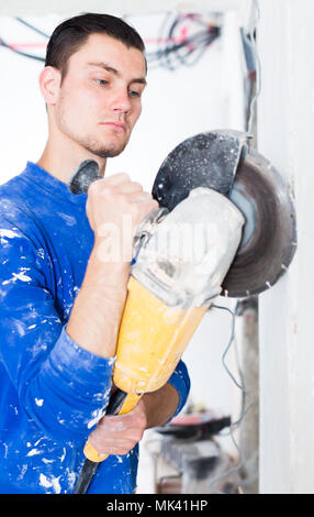 Construction worker cutting concrete wall by using handheld circular saw Stock Photo