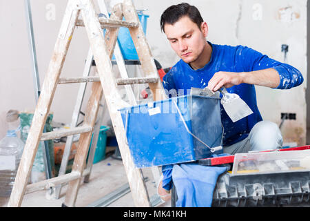 Young builder handyman choosing necessary tool in toolbox Stock Photo