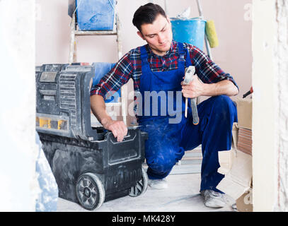 attentive builder handyman choosing necessary tool in toolbox Stock Photo