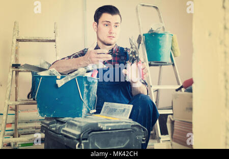 Young professional builder handyman choosing necessary tool in toolbox Stock Photo