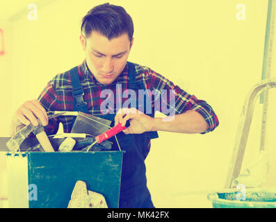 Handyman searching in his toolbox for necessary tools Stock Photo