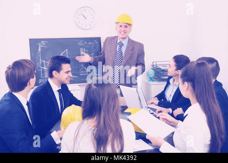 Group of engineers discussing business project and smiling indoors Stock Photo