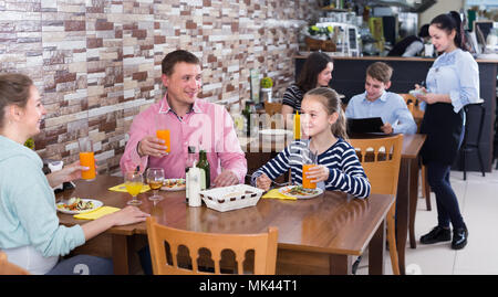 Cheerful family with teenagers having lunch in cozy cafe Stock Photo