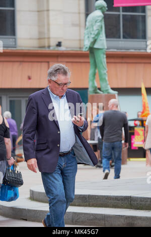 Man walking in the street, using his mobile phone Glasgow Scotland Stock Photo