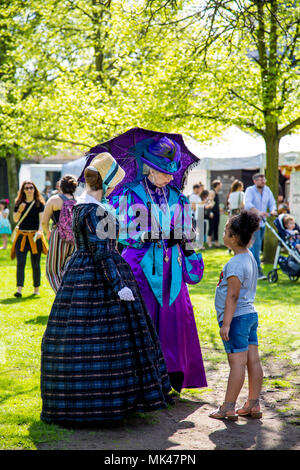 Two victorian ladies standing in a garden taking with a young girl at the Fes-Tea-Val 2018 on National Tea Day in Chiswick House & Gardens, London, UK Stock Photo