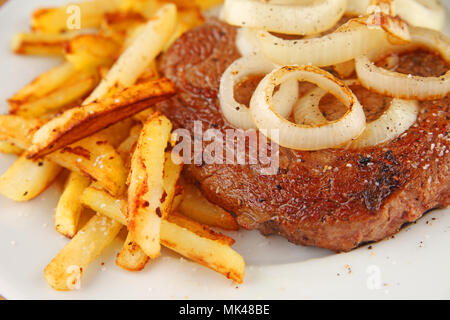 Steak with sauteed onions and french fries Stock Photo