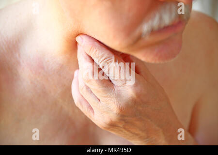 An older man touches his painful throat with his fingers Stock Photo