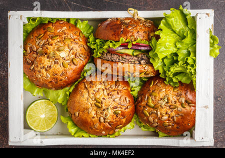 Vegan bean burger with vegetables and tomato sauce in white wooden box, top view. Healthy vegan food concept. Stock Photo