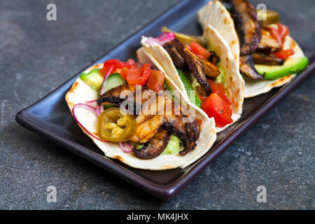 Vegan tortillas with mushrooms, avocado, pickled onions and cucumber Stock Photo