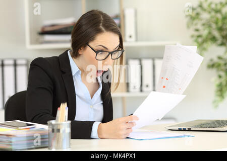 Amazed executive checking sales results in several documents at office Stock Photo