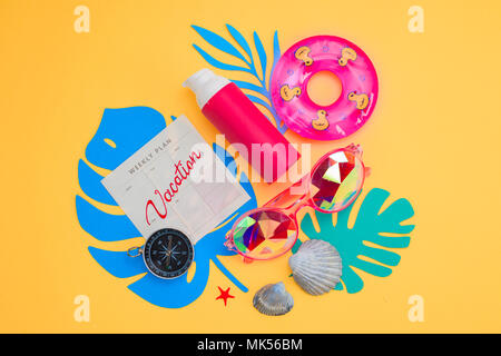 Summer vacation flat lay with beach accessories and tropical leaves on a vibrant yellow background. Travel essentials from above with copy space. Modern colorful palette. Stock Photo