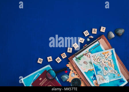 Sea travel and exploration concept. Watercolor maps, passport, compass, binoculars, envelopes, magnifying glass, and Wanderlust scrabble letters flat lay on a navy blue background with copy space