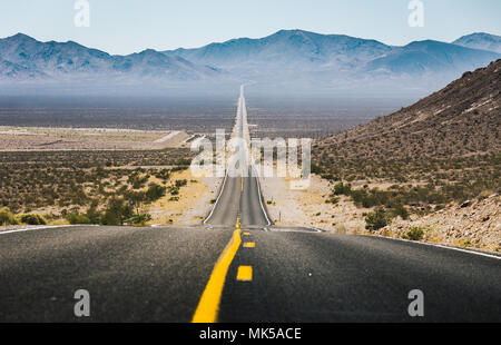 Classic panorama view of an endless straight road running through the barren scenery of the American Southwest Stock Photo