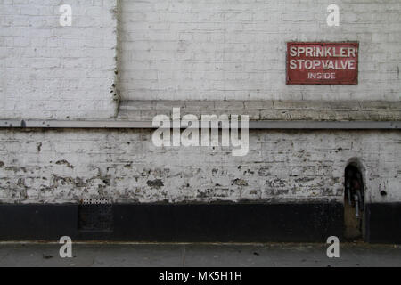 Sprinkler Stop Valve Sign on a white painted brickwork brick wall Stock Photo