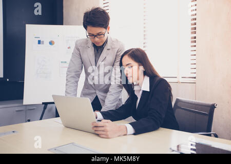 Asian businessmen and group using notebook for business partners discussing documents and ideas at meeting and business women smiling happy for workin Stock Photo