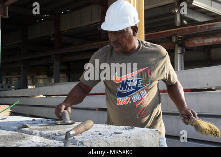 SAN JUAN, Puerto Rico – A worker puts the finishing touches on a utility pole at Power Precast Corp. in Rio Grande, Puerto Rico Nov. 13, 2017.  The reinforced concrete poles are intended to replace those that were knocked down by Hurricane Maria to reinstate the critical infrastructure on the island territory. (US Army photo by Spc. Samuel D. Keenan) Stock Photo