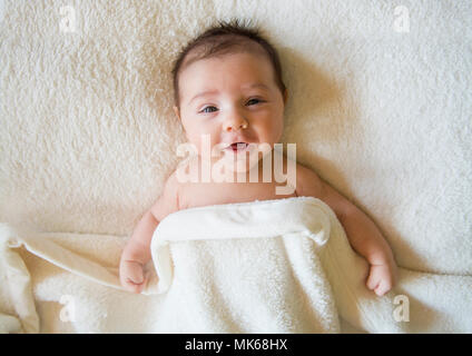 Cute baby boy in bed under a blanket Stock Photo