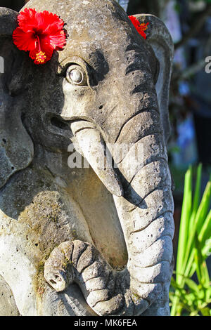 Statue of Ganesha, a Hindu god in the shape of an elephant with red hibiscus flowers, Bali, Indonesia Stock Photo