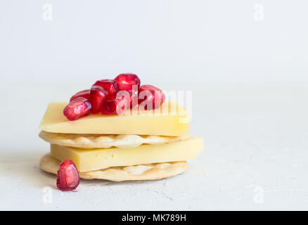 Cheese and crackers with pomagranate seeds isolated on rustic white background Stock Photo