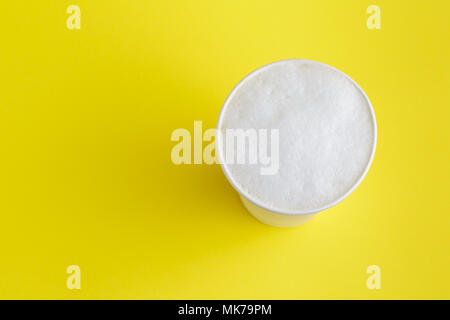 Top view of take-out coffee Latte in opened thermo cup on vibrant yellow background Stock Photo