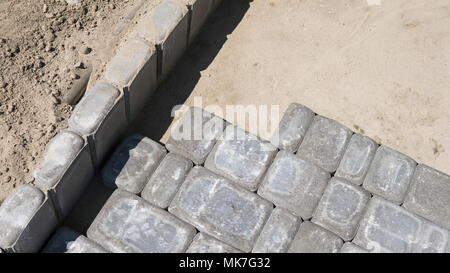 Process of fitting laying new exterior paving stones carefully placing one in position on a leveled and raked soil base. Sand foundation. Building. Stock Photo