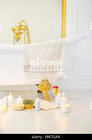 Close up of candles, book, glass of champagne by the bath on the marble tiled floor Stock Photo