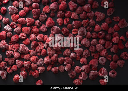 Top view of frozen raspberries spread on the black table. Stock Photo