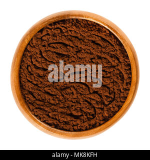 Fine cocoa powder in wooden bowl. Processed and alkalized cocoa solid with dark brown color, used for baking and in beverages. Isolated macro photo. Stock Photo