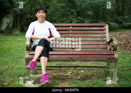 Senior woman relaxing on park bench Stock Photo