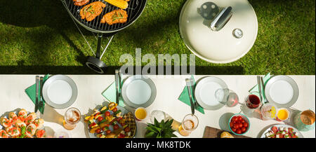 Table with barbecue food and white tablecloth from high angle Stock Photo