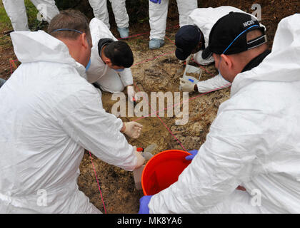 Participants examine a simulated hidden ‘grave site’ during a clandestine grave and human remains recovery training at Joint Base Charleston, S.C., Nov. 14, 2017. Participants were divided into three groups to analyze and find the three different crime scenes, all while cross training with different agencies. (Photo by Airman 1st Class Allison Payne) Stock Photo