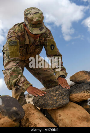 U.S. Army National Guard Sgt. Gabriel Mancera, 3rd Battalion, 144th Infantry Regiment, Task Force Bayonet, stacks rocks as he sets up a defensive position on the first day of a French Desert Commando Course at the Djibouti Range Complex near Arta, Djibouti, Nov. 26, 2017. The 12-day course will expose service members to the fundamentals of desert combat, survival, and troop movements while also bridging language and cultural barriers between the French and American troops. (U.S. Air Force photo by Staff Sgt. Timothy Moore) Stock Photo
