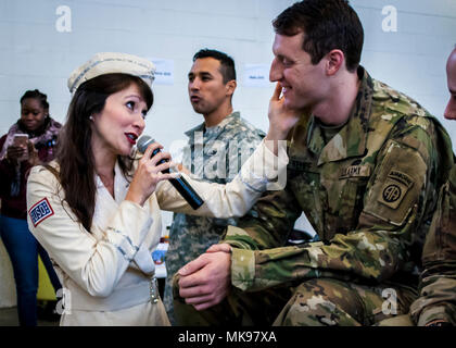 Amanda Downey, a member of the New York City based USO Show Troupe, sings a song to 1st Lt. Alexander Kempf, 32nd Engineer Company, 2nd Brigade, 82nd Airborne Division, during the lottery portion of the 20th Annual Randy Oler Memorial Operation Toy Drop, Dec. 1, 2017. Operation Toy Drop, hosted by the U.S. Army Civil Affairs &amp; Psychological Operations Command (Airborne) and is the largest combined airborne operation conducted worldwide. The event and allows Soldiers the opportunity to train on their military occupational specialty, maintain their airborne readiness, and give back to the lo Stock Photo