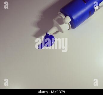 Paint bottle with paint spilled on a table. Concept creativity, art creation, minimalism. Stock Photo