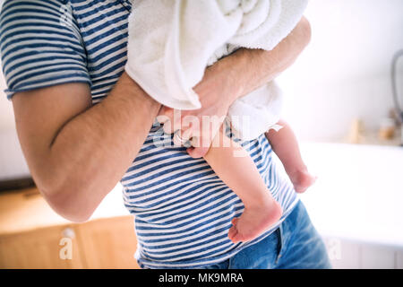 Unrecognizable father with a toddler child wrapped in towel in a bathroom at home. Stock Photo