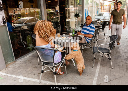 Tel Aviv, Israel. People with their dog are relaxing in cafe on the street located near the beach Tel Baruch. Stock Photo