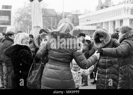 Women, men and children are dancing in the square in the center of Tiraspol, Moldova at the Shrovetide Festival. The reportage photo is black and whit Stock Photo