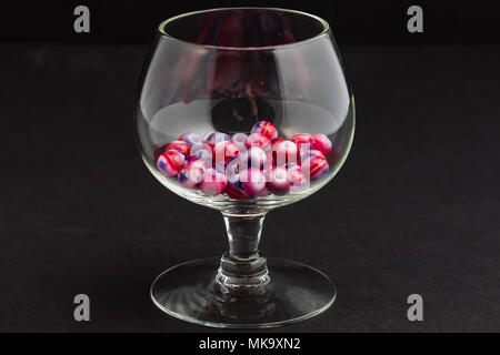 several red white and blue jewelry beads in a small clear glass goblet Stock Photo