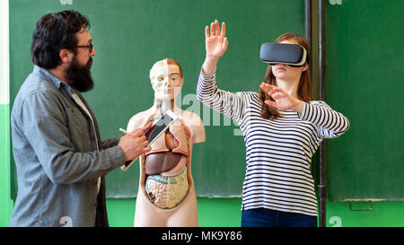Young teacher using Virtual Reality Glasses and 3D presentation to teach students in biology class. Education, VR, Tutoring, New Technologies and Teac Stock Photo