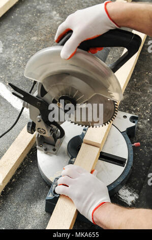 Worker cuts wood bars using a circular saw. Stock Photo
