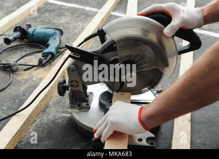Worker cuts wood bars using a circular saw. Stock Photo