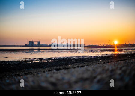 Sunset over Southampton Docks during low tide, view from Weston Shore, Hampshire, England, UK Stock Photo
