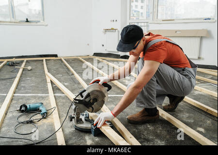 Worker cuts wood bars using a circular saw. Stock Photo